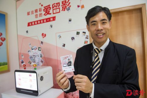 在血液中心新推出的“爱留影”相片打印机前，无偿献血者乔彬向记者的镜头展示刚打印好的照片。据了解，献血者只需要用微信“扫一扫”，就能现场打印出用手机拍摄的照片。
