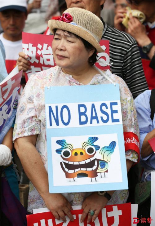 　6月19日，在日本首都东京，一名市民胸前挂着“不要（美军）基地”的标语。