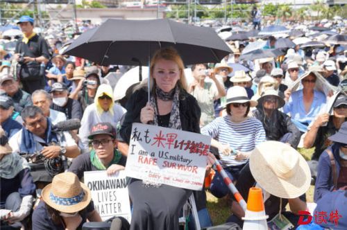 6月19日，在日本冲绳县首府那霸市一座公园内，一名抗议者手举“我是美军暴行受害者”的标语。