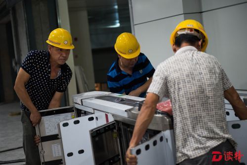 01华强北站2、7号线换乘通道内，工人安装闸机。