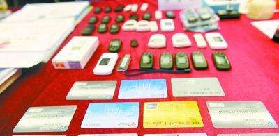 广东警方展示缴获的电信诈骗涉案银行卡、电子密码器等。