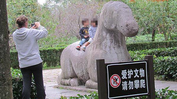 老外妈妈游景区 抱孩坐600多年神兽拍照