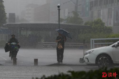 在南山区世界之窗地铁站附近，行人在暴雨中等待红灯转绿。