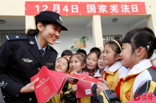 2014年12月3日，民警在山东省枣庄市文化路小学“国家宪法日”系列活动中向学生们赠送《宪法》单行本。