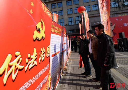 2014年12月4日，西安市民在宪法日宣传活动现场观看依法治国宣传展板。