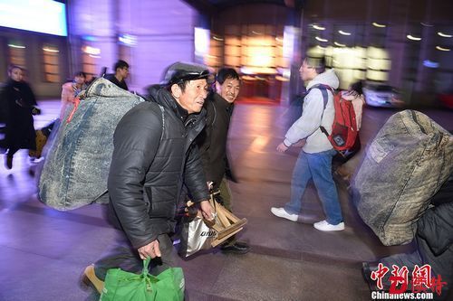 1月13日，旅客扛起行李准备登车。 中新网记者 金硕 摄