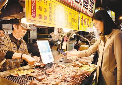 顾客在台北宁夏夜市烤肉摊前使用支付宝扫码付款。本报记者 冯学知摄