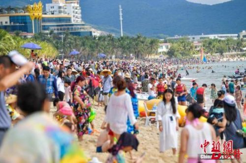 资料图 三亚大东海沙滩上，数万游客畅享椰风海韵阳光沙滩。 中新社记者 骆云飞 摄