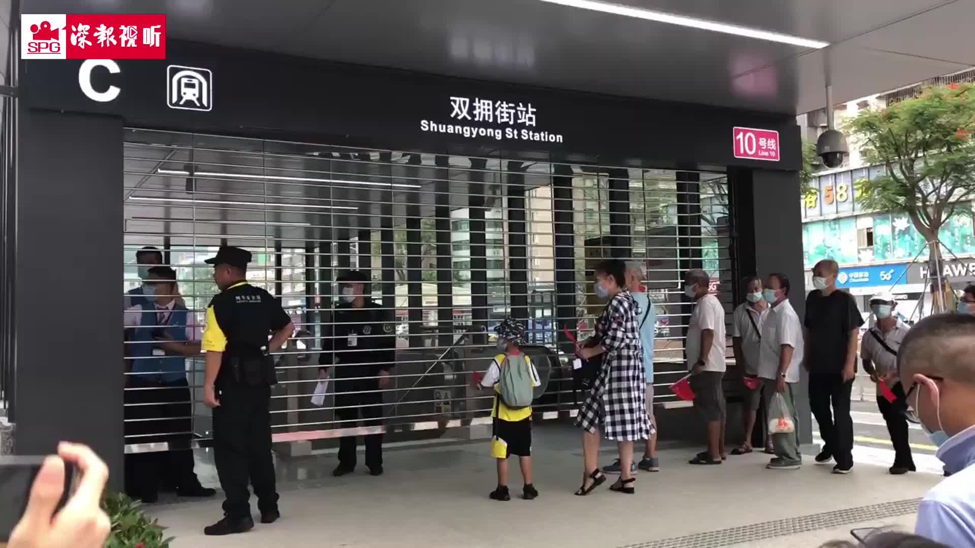 深圳地铁10号线正式开通 市民举着国旗等待