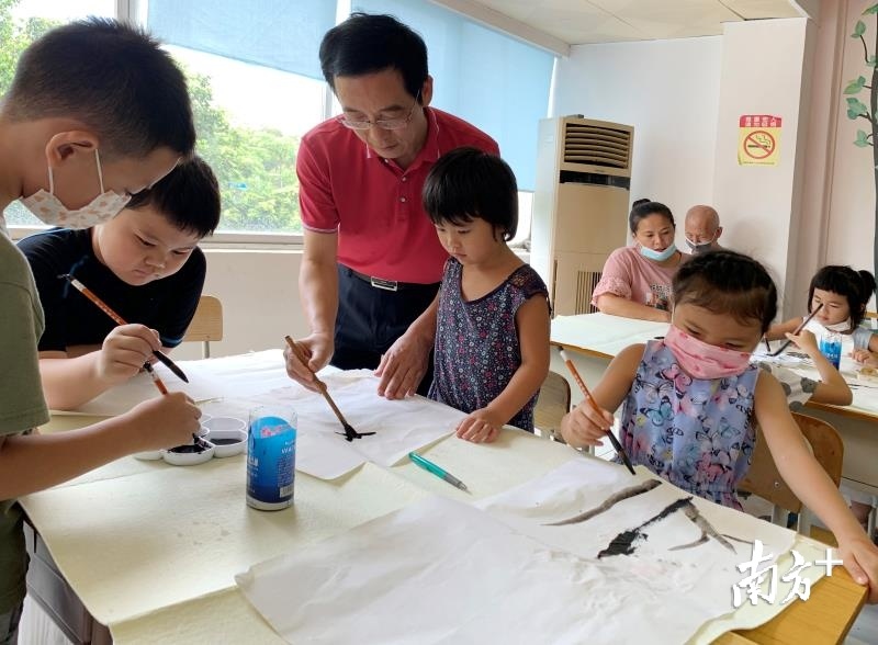九洲社区党委与辖区企事业单位党组织签订结对共建协议，建立起“社区吹哨，党员报到”项目。图为共建单位的老师为孩子们开讲“书画第一课”。 关铭荣 摄
