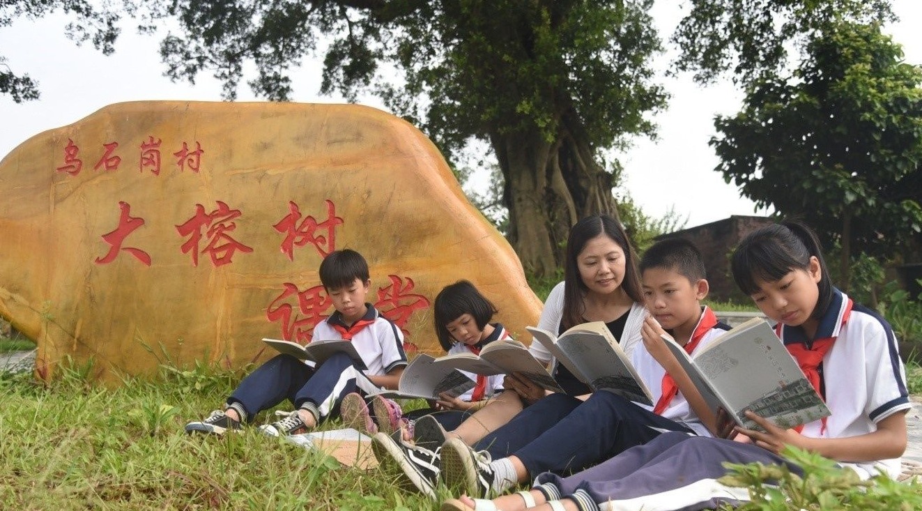 四会师生在乌石岗村大榕树课堂阅读该市纪委编印的家风教育读本《古邑家训颂清风》。