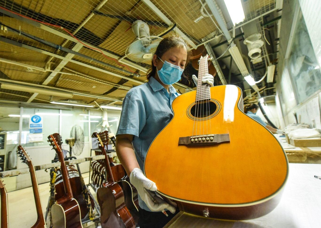 经过三十余年的耕耘，惠阳已全国最大的吉他生产基地。图为吉他企业工人正在制作吉他