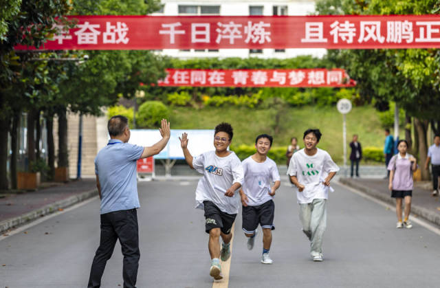 6月7日，在贵州省黔西一中考点，考生与老师击掌鼓劲后奔赴考点。  新华社发（范晖摄）
