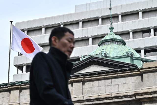 3月19日，在日本东京，行人经过日本央行总部。新华社发