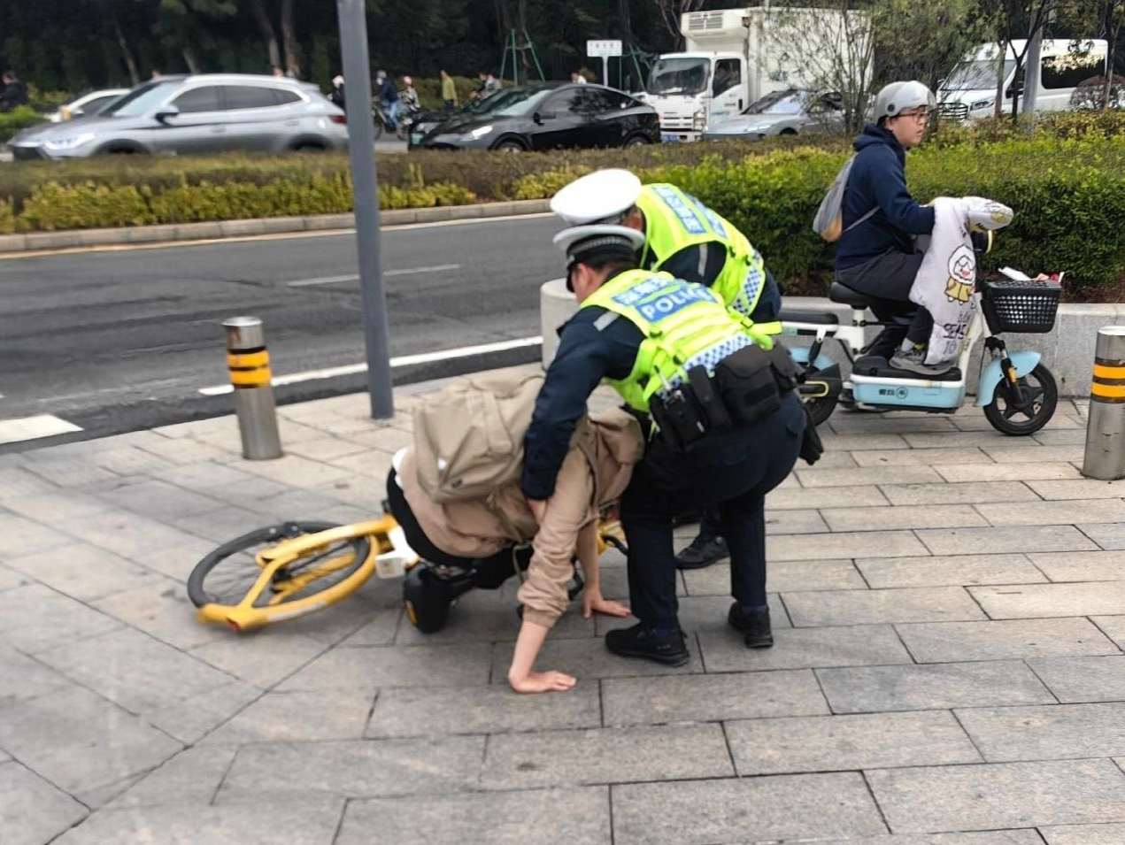 深圳街头一名男子骑车倒地，他们迅速上前用身体护住