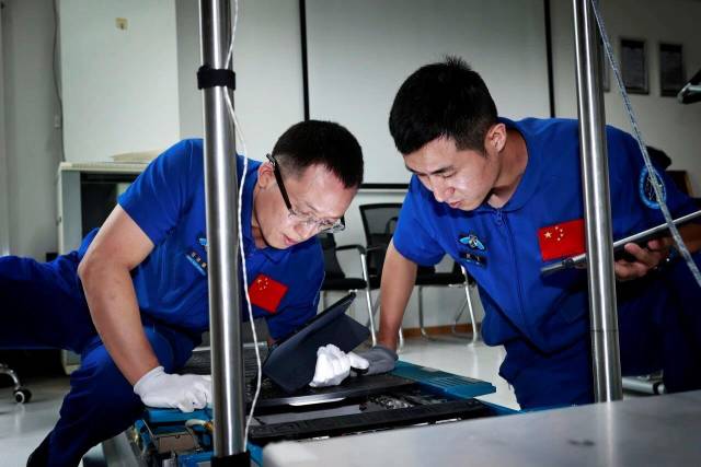△航天员张洪章（左）、武飞（右）在进行设备维修训练