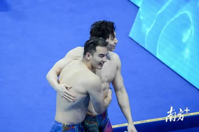 11月13日晚，在第十五届全国运动会男子50米蛙泳决赛中，上海队覃海洋（右）因抢跑犯规被取消成绩，同队队友郑英昊摘得金牌，赛后两人相拥。张令 摄